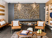 Thumbnail 41 of 68 - Cozy communal lounge in the apartment complex featuring stylish seating arrangements, a modern flat-screen TV, a warm fireplace, and a tabletop shuffleboard for residents to enjoy.