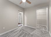 Thumbnail 32 of 68 - A room with a ceiling fan and a carpeted floor.