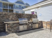 Thumbnail 24 of 25 - an outdoor kitchen with two grills in front of a house at The Retreat at Sumter, Sumter, South Carolina