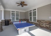 Thumbnail 23 of 25 - a patio with a ping pong table and a ceiling fan at The Retreat at Sumter, Sumter, South Carolina