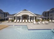 Thumbnail 21 of 25 - a resort style pool with lounge chairs and umbrellas at The Retreat at Sumter, Sumter, South Carolina