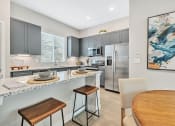 Thumbnail 2 of 14 - a kitchen with stainless steel appliances and a table and chairs at Avilla Towne Center Apartments, Texas