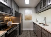 Thumbnail 23 of 32 - a kitchen with stainless steel appliances and white counter tops and a sink