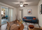 Thumbnail 11 of 31 - a living room with a blue couch and a ceiling fan at The Fountains Apartments, Pensacola, FL