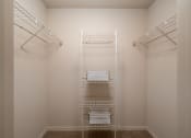 Thumbnail 25 of 31 - a walk in closet in a small room with white walls and white shelves and racks at The Fountains Apartments, Pensacola, Florida