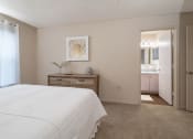 Thumbnail 24 of 31 - a bedroom with a white bed and a bathroom with a sink at The Fountains Apartments, Pensacola, FL