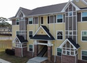 Thumbnail 1 of 31 - an apartment building with yellow siding and a staircase at The Fountains Apartments, Pensacola, 32514