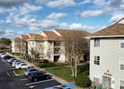 Thumbnail 8 of 31 - a row of houses with cars parked in a parking lot at Tivoli Apartments of Orlando, Oviedo, FL