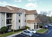 Thumbnail 7 of 31 - an apartment building with cars parked in a parking lot at Tivoli Apartments of Orlando, Oviedo