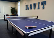 Thumbnail 15 of 31 - a blue ping pong table in a room with a scoreboard on the wall at Tivoli Apartments of Orlando, Oviedo, FL, 32765