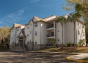 Thumbnail 6 of 39 - an apartment building on a street with palm trees at Stoneridge Apartments, Gainesville, FL