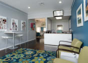 Thumbnail 10 of 39 - a leasing office with blue walls and a blue rug and a reception desk at Stoneridge Apartments, Gainesville, Florida, 32608