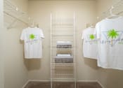 Thumbnail 24 of 39 - a closet with white shirts and a rack with towels on it at Stoneridge Apartments, Gainesville, 32608