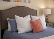 Thumbnail 32 of 39 - a bed with blue sheets and pillows and a brown headboard at Stoneridge Apartments, Gainesville, Florida
