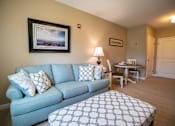 Thumbnail 5 of 5 - A living room with a blue couch and a painting on the wall.