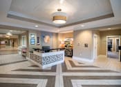 Thumbnail 2 of 5 - A reception area with a white reception desk and a patterned tile floor.