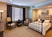 Thumbnail 5 of 5 - A bedroom with a bed, chair, and table at The Piper, Kansas City, KS.