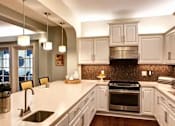 Thumbnail 4 of 5 - A modern kitchen with white cabinets and a dark backsplash at The Piper, Kansas City, KS.