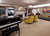 Thumbnail 3 of 5 - A living room with a piano, sofa, and chairs at The Piper, Kansas City, KS.