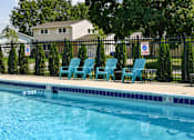 Thumbnail 17 of 35 - Outdoor pool with turquoise lounge chairs and black fence at Fox Run Apartments, St. Charles, IL
