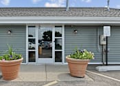 Thumbnail 19 of 35 - Building entrance with terracotta planters and glass doors at Fox Run Apartments, St. Charles