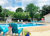 Thumbnail 16 of 35 - Outdoor pool with turquoise chairs and fence at Fox Run Apartments, St. Charles, Illinois