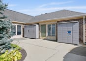 Thumbnail 23 of 28 - the front entrance of a brick house with two garage doors at Aspen Ridge Apartments, West Chicago