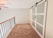 Thumbnail 12 of 35 - Carpeted loft space with barn door closet at Fox Run Apartments, St. Charles