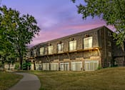 Thumbnail 15 of 35 - Brick apartment building exterior at twilight with garages at Fox Run Apartments, Illinois, 60174