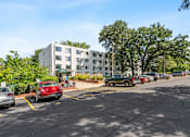 Thumbnail 4 of 23 - a parking lot with cars in front of an apartment building