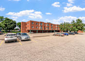 Thumbnail 21 of 25 - a parking lot with cars in front of a brick building
