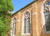 Thumbnail 43 of 45 - the side of a brick church with stained glass windows
