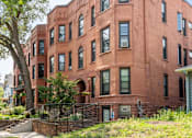 Thumbnail 45 of 67 - a red brick apartment building with a sidewalk and grass