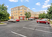 Thumbnail 12 of 35 - a parking lot with cars in front of an apartment building