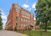 Thumbnail 17 of 31 - a large red brick building with a black wrought iron fence