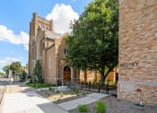 Thumbnail 42 of 45 - the outside of a brick church with a sidewalk and a tree