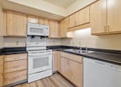 Thumbnail 21 of 23 - A kitchen with wooden cabinets and black countertops.