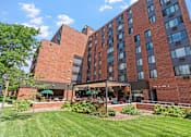 Thumbnail 3 of 55 - a large brick building with a lawn and garden in front of it