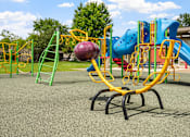 Thumbnail 27 of 41 - a playground with a blue and yellow swing set and a large ball