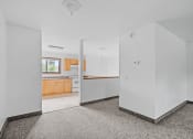 Thumbnail 24 of 43 - the living room and kitchen of a home with white walls and wood cabinets