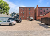 Thumbnail 40 of 67 - a large red brick building with cars parked in a parking lot