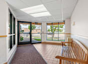 Thumbnail 9 of 25 - a lobby with a bench and glass doors