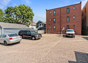 Thumbnail 39 of 67 - a large parking lot with cars in front of a brick building