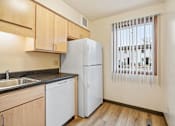 Thumbnail 19 of 23 - A kitchen with a white refrigerator, wooden cabinets, and a window with blinds.