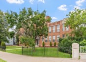 Thumbnail 14 of 31 - a large brick building with a lawn and trees in front of it