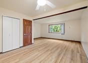 Thumbnail 17 of 23 - A room with a brown door and a window with a view of trees.
