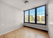 Thumbnail 14 of 24 - an empty living room with a large window and wood flooring