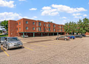 Thumbnail 20 of 25 - a parking lot with cars in front of a brick building