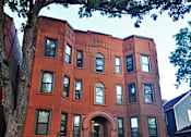 Thumbnail 67 of 67 - a red brick building with stairs and a tree in front