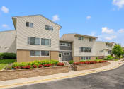 Thumbnail 2 of 57 - an apartment building with a stone retaining wall and flower beds
